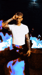 a man with tattoos on his arms is standing in front of a blue and white background