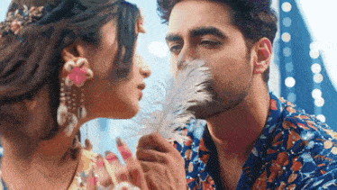 a man is kissing a woman on the cheek with a white feather