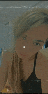 a woman in a black tank top is taking a picture of herself in the mirror .