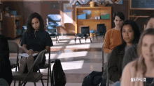 a group of people sitting in a classroom with a netflix logo on the bottom