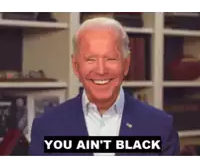 a man in a suit is smiling with the words you ain 't black above him
