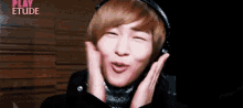 a young man wearing headphones making a funny face in front of a play etude sign
