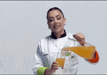 a woman in a chef 's uniform is pouring a drink into a glass