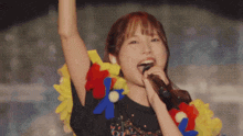 a woman singing into a microphone wearing a floral lei around her neck