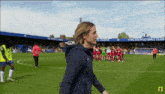 a man walks on a soccer field in front of a banner that says chelsea football club