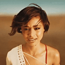 a woman with short hair is making a funny face while standing in the desert .