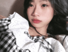 a woman wearing a black and white checkered shirt with white ruffles