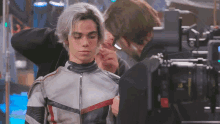 a man is adjusting a man 's earring in front of a camera