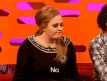 a woman in a black dress says no in front of a man in a plaid shirt
