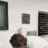 a woman looks down at a painting on a white wall