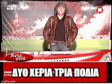 a man in a leather jacket is standing in front of a soccer field on a tv screen .
