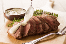 a steak with sauce being poured on it is on a cutting board