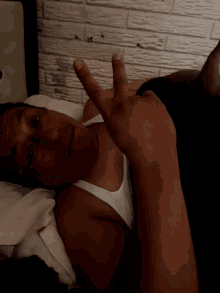a man in a white tank top is laying on his back with his head upside down