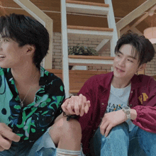 two young men sitting next to each other with one wearing a t-shirt that says mais