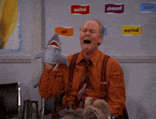 a man is holding a stuffed animal in front of a wall with signs that say excited stressed sad and worried