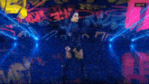 a female wrestler is standing in front of a wall with graffiti on it including the word riot