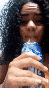 a woman with curly hair is drinking a can of diet dr pepper