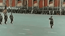 a group of soldiers are marching down a street in a parade .