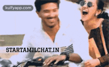 a man and a woman are sitting on a motorcycle and laughing .