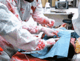 a man in bloody gloves is cutting a person 's arm