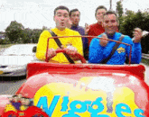 a group of men are riding in a red car that says wiggles on it .
