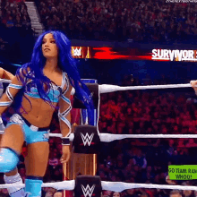 a woman with blue hair is standing in a wrestling ring with a sign that says survivor