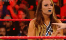 a woman is standing in a wrestling ring talking to a man .