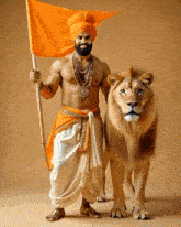 a man in an orange turban is holding an orange flag and standing next to a lion