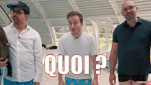 three men are standing in front of a sign that says quoi on it