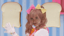 a girl with pink hair and a yellow bow holds two slices of bread