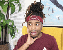 a man with dreadlocks wearing a red bandana and a maroon shirt
