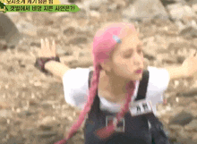 a woman with pink hair is standing with her arms outstretched