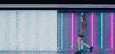 a woman is walking in a room with neon lights behind her .