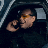 a man wearing safety glasses is talking on a cell phone