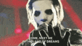 a man in a mask is singing into a microphone while wearing gloves .