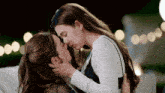 a couple of women are kissing each other on the forehead .