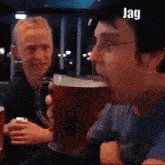 a man is drinking a beer from a mug while a woman watches .