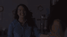 a woman in a polka dot shirt is smiling while holding another woman 's hand