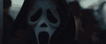 a close up of a scream mask with a black hood on .
