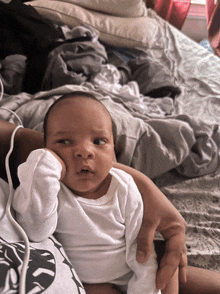 a person is holding a baby in their arms and the baby is looking at the camera