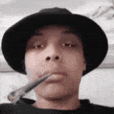 a person wearing a black hat is smoking a cigarette .