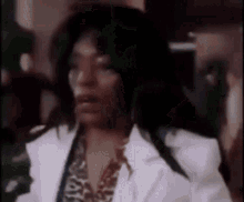 a close up of a person wearing a white coat and a leopard print shirt .
