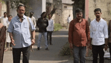 a group of men are standing on a street .