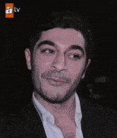a close up of a man 's face with a tv logo on the bottom right