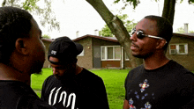 three men are standing in front of a house and one of them is wearing a shirt that says ' inn '