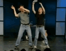 two men are dancing on a stage with their arms up in the air