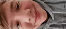 a close up of a person 's face wearing a grey hoodie with the letter j on it