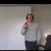 a young man wearing headphones is holding a red remote control in his hand .