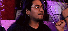 a man with long hair and glasses is holding a pair of scissors in his hand
