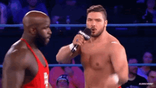 a shirtless wrestler is talking to another wrestler in a wrestling ring .